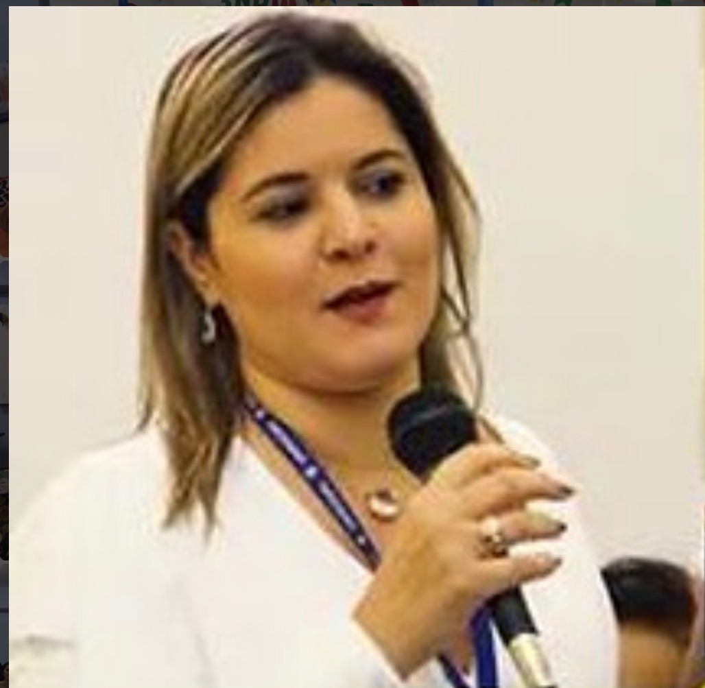 Andréa Amaral falando ao microfone em evento jurídico